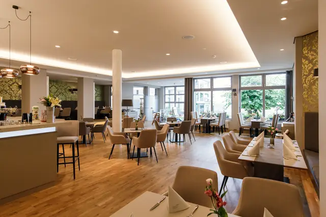 Heller Restaurantbereich im Luisenhof Dresden mit Fensterplätzen, Holzboden, Sitzgruppen und indirekter Beleuchtung