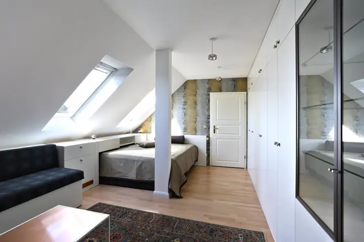 Heller Dachgeschossraum mit maßgefertigten Einbauschränken, Stauraummöbeln und integriertem Bett